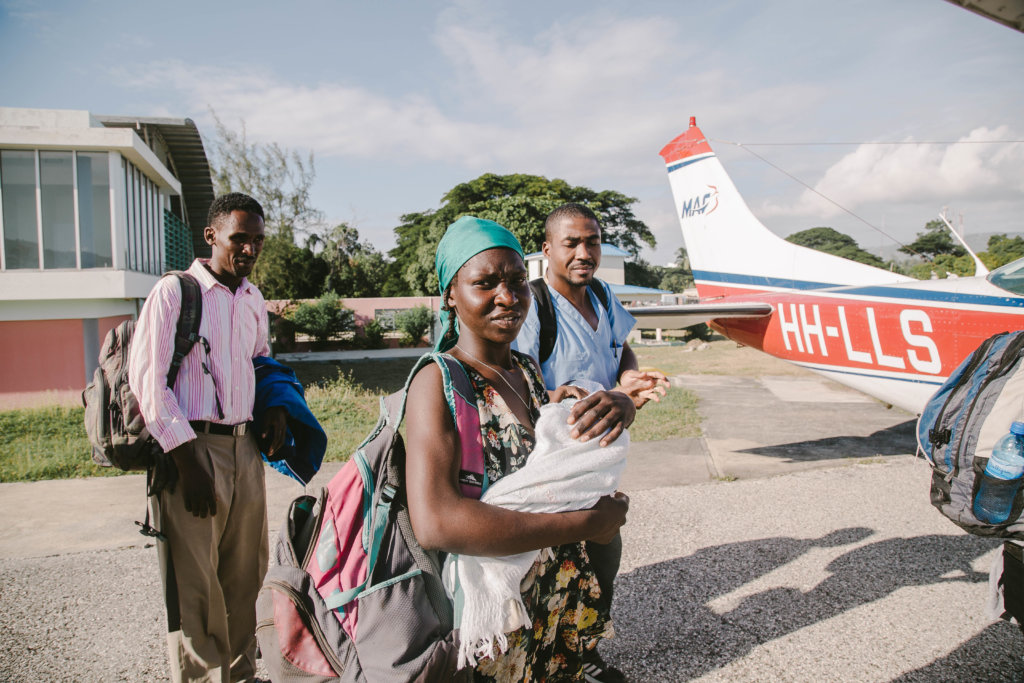 Mother cradles her malnourished infant and prepares to board MAF charity plane in Haiti.