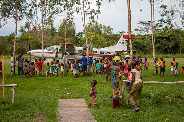 An MAF airplane lands on Kikongo's grass airstrip on a previous carefree day. Photo by Mark and Kelly Hewes.