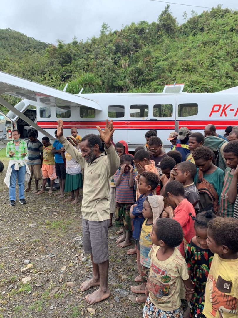 Man leads prayer of thanksgiving after MAF charity pilots deliver Bibles in Silimo Papua Indonesia